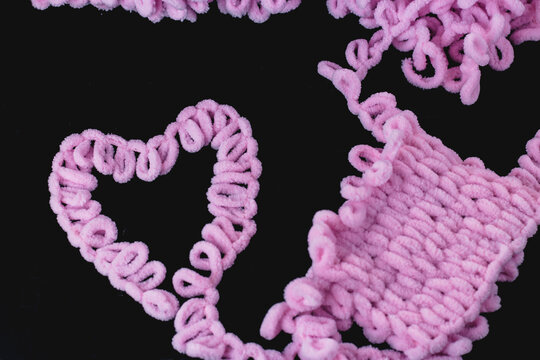 Pink yarn for knitting with your fingers. Alize yarn. Black background. Heart