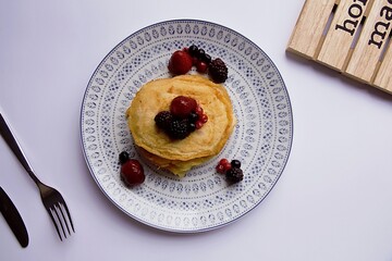 pancakes with red berries on white background