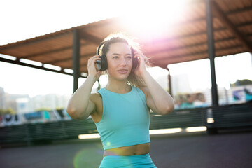 Young sporty woman with headphones. Beautiful woman listening the music while preparing for the training.