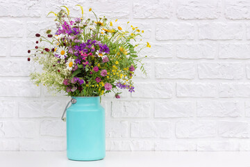 Bouquet of bright flowers in tin can vase on background white brick wall. Template for postcard. Concept Women's day, Mothers Day, Hello summer or Hello spring