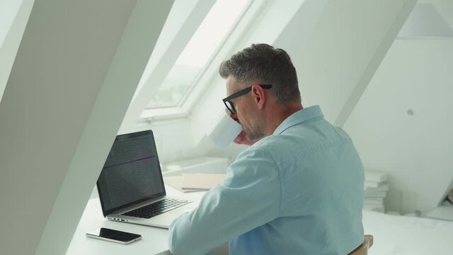 Confident mature man working on laptop while sitting at the office desk