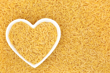 Orzo pasta health food in a heart shaped dish. Suitable for vegan,  vegetarian diet, gluten free, high in fibre, vitamins, minerals. Flat lay, top view.