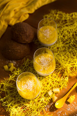 Chia pudding or smoothie with mango puree, coconut milc and coconut chips in transparent glasses  