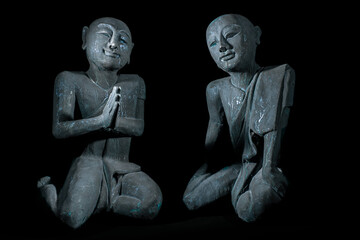 Buddhist monks in peaceful meditation. Traditional vintage Thai buddhism statues isolated over black background