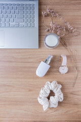 Beauty blog fashion concept. Female styled accessories: laptop, scrunchie, wildflowers and cosmetics on wooden background. Flat lay, top view trendy feminine background.