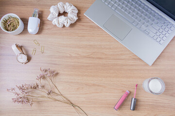 Fototapeta na wymiar Beauty blog fashion concept. Female styled accessories: laptop, scrunchie, wildflowers and cosmetics on wooden background. Flat lay, top view trendy feminine background.