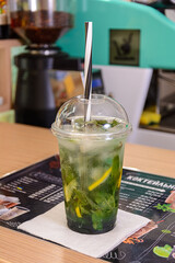 A glass plastic cup with mojito on a table