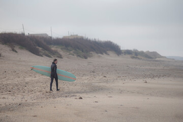 surfer walking alone on the beach