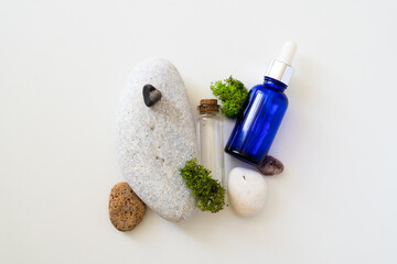 Sea moss personal care. Blue bottle with oil dropper and sea stones and moss on white background. Ingredient for skincare