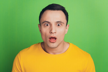 Portrait of shocked speechless guy open mouth stunned face on green background