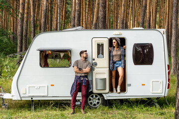 Young couple spending summer vacation in mobile house in pinetree forest