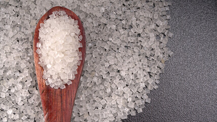 Sugar in glass bowl on wooden background.