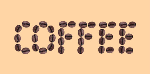 Coffee word laid out from roasted aromatic robusta beans on brown background
