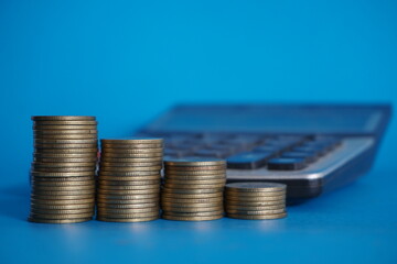 stacks of money coin with calculator and book bank, Business and financial investment concept on blue background