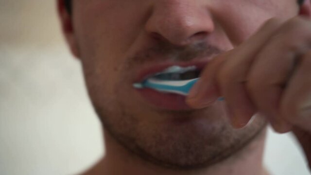 camera shoots a man brushing his teeth close-up