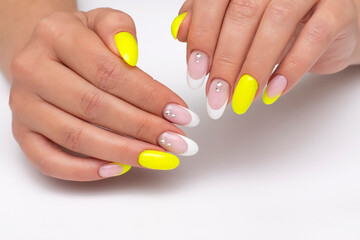 Summer bright yellow, white manicure with crystals, sparkles on long oval nails on a white background, close-up. French manicure with decoration.