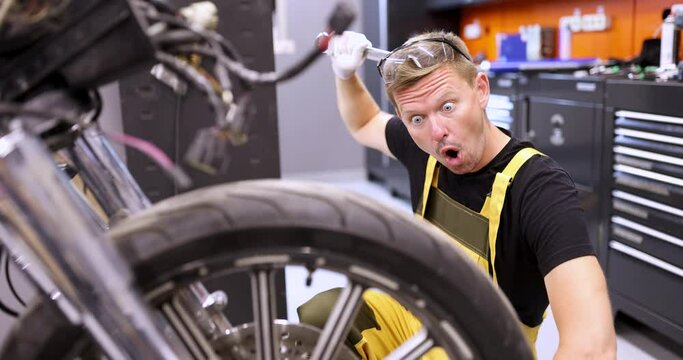 Surprised man repairman repairing motorcycle and scratching his head with wrench 4k movie