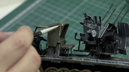 Scale Modeling. A man making Weathering on 1:35 plastic model of German 8ton Semi Track with 20mm flakvierling . Close up. 