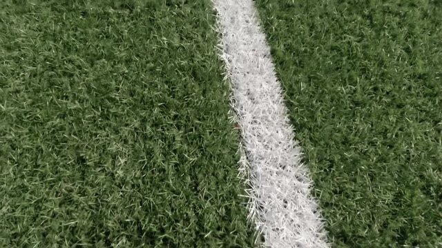White stripe line on artificial green soccer field background from above. Close up
