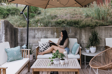 Young adult Filipino woman writing and journaling outdoors at home on patio