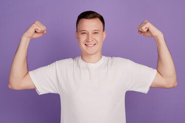 Portrait of cool strong guy raise hands show muscle on violet background