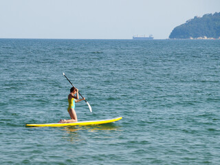 teenage girl riding a sup-board in the sea on her knees