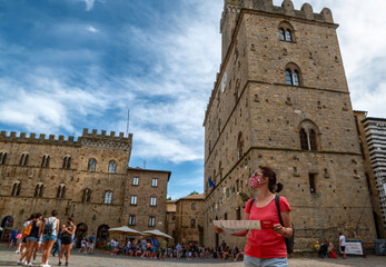 Volterra, Tuscany, Italy. August 2020. In piazza dei priori a middle-aged woman consults the...