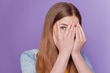 Portrait of frightened lady palm cover face peek eye wear jeans clothes on purple background