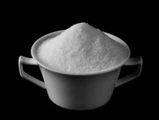 Sea salt crystals pile in porcelain cup isolated on black background