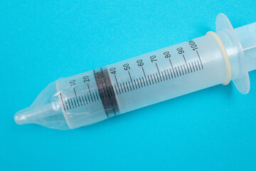 Safe Vaccine, Anti Vaccination Concept - Syringe in a Condom Lay on Blue Table in Clinic or Hospital. Mistrust of Vaccination. Natural Immunity. Skepticism About the Vaccine. Freedom and Human Rights