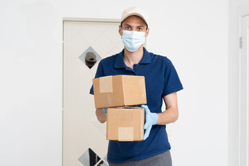 Fototapeta na wymiar Man from delivery service in t-shirt, in protective mask and gloves giving food order and holding boxes over white background.