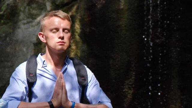 A man meditates listening to the murmur of a waterfall