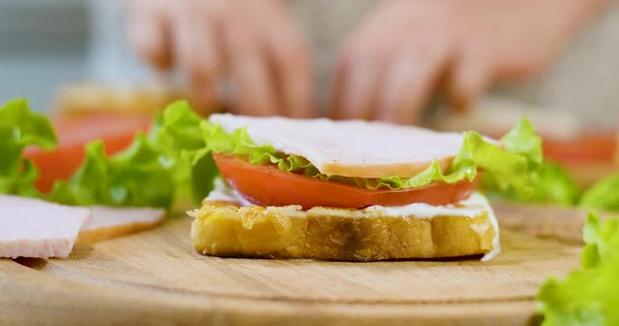 Female chef in the kitchen of the house collects a sandwich