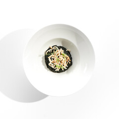 Risotto with cuttlefish black ink. Black risotto plate isolated on white background. Risotto with...