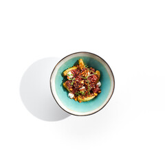 Tuna and cucumber salad bowl. Blue salad bowl isolated on white background. Salad garnished with micro greens and sesame, chopped tuna, sliced cucumber and parsley green leaf.