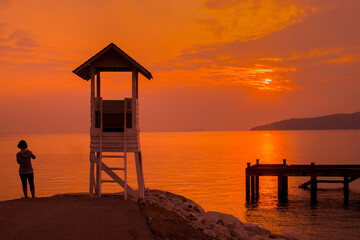 A tourist and silhouette of a small pavilion with last sun light in evening at Khao Leam Ya ,Thailand that is relaxing picture.
