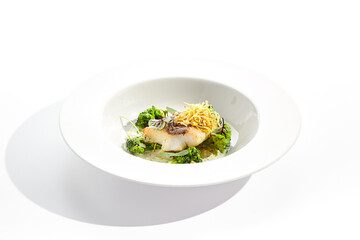 Panfried Fish with broccoli and cream sauce. Healthy roasted cod with green leaves. Fried Fish on white restaurant plate isolated on white background.