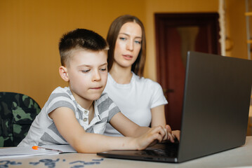 A mother and her child are engaged in distance learning at home in front of the computer. Stay at home, training