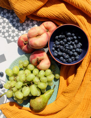 Still life with fruits and berries. Organic berries and fruits on a table. Garden harvest close up photo. Pears, peaches, red currant, blueberry, grapes top view photo. Healthy eating concept. 