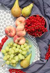 Summer fruits and vegetables on a table. Top view photo of red currant, blueberry, pears, grapes, peaches on blue textured fabric background. Still life with organic fruits. 