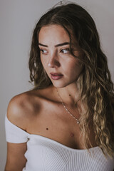 Fototapeta na wymiar Portrait of relaxed young female model , with natural makeup, wavy hair, dressed in white clothes on background .People, beauty, face care