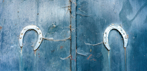 2 herraduras de metal sobre una puerta azul con texturas. como amuleto.
