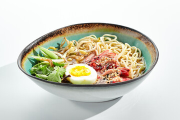 Ramen Chicken Soup - traditional soup with chicken and ramen noodles and other ingredients. Topped with eggs. Ramen soup bowl isolated on white background.