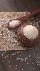 Sugar in glass bowl on wooden background.