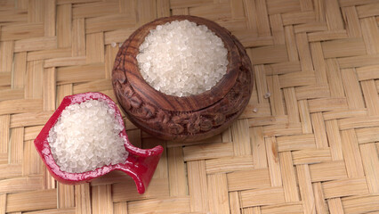 Sugar in glass bowl on wooden background.