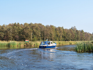 Fototapeta na wymiar Motorboat cruising on canal in nature reserve Alde Feanen, Friesland, Netherlands
