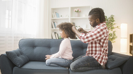 Caring father combing afro hair of little daughter, morning routine, parent love