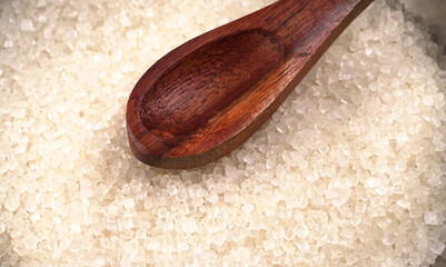 Bowl and spoon with sugar on wooden background.