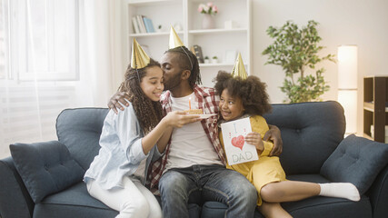 Two daughters wishing happy birthday to their father, celebrating with cake and presents