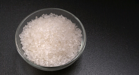 Bowl and spoon with sugar on wooden background.
